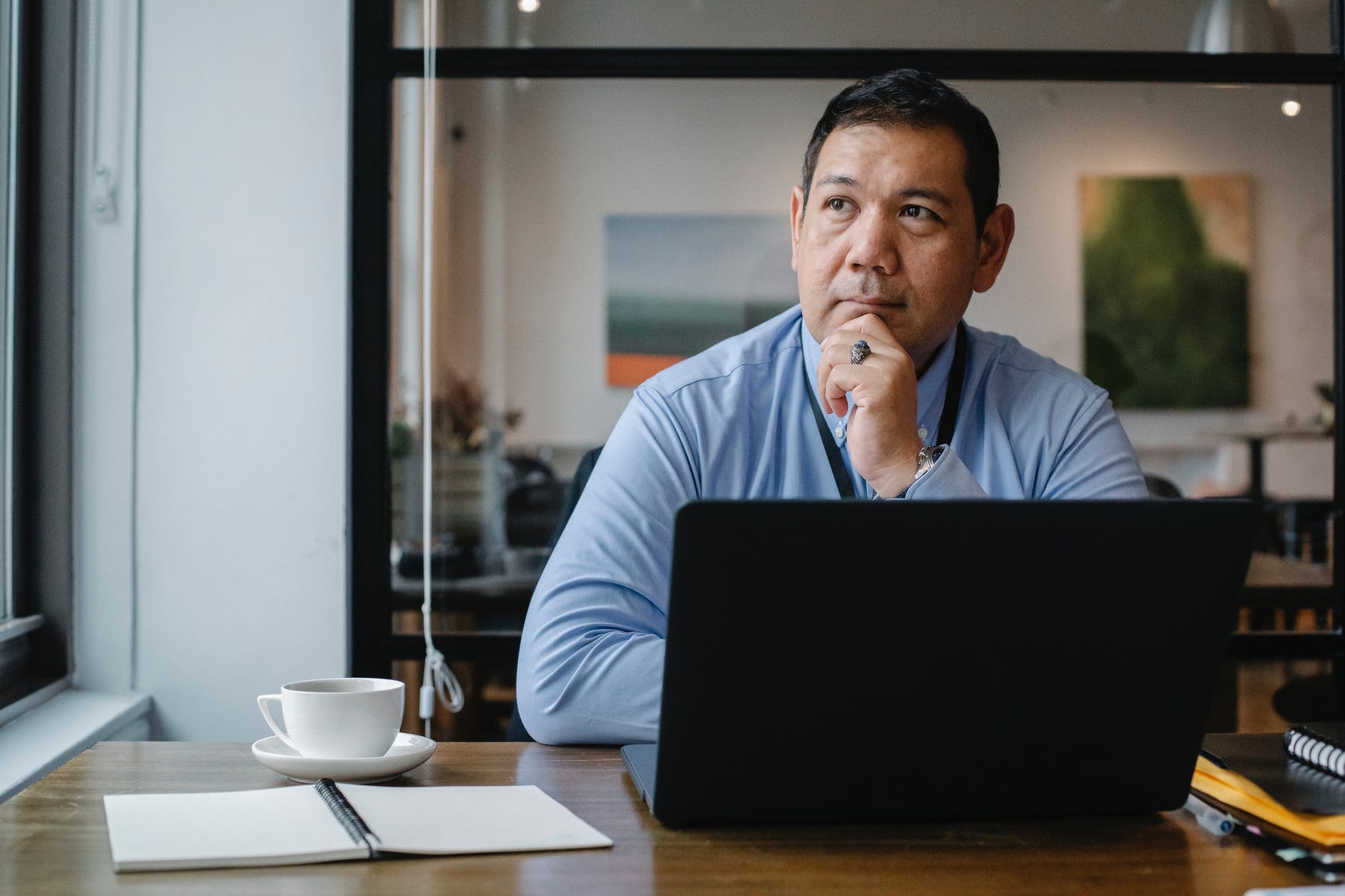 thoughtful ethnic businessman using laptop while working in office